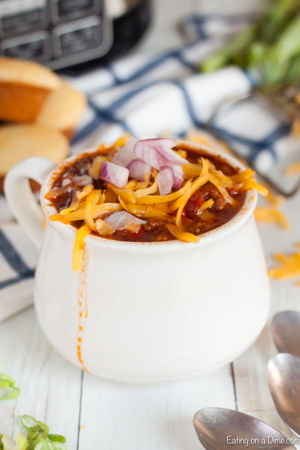 A bowl of cowboy chili topped with cheese, sour cream and red onions. 