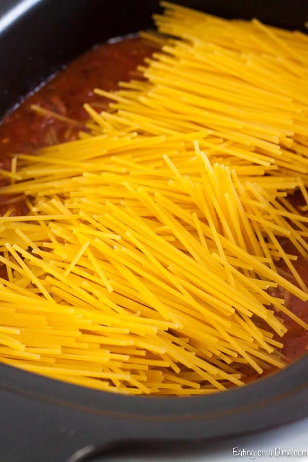 Adding spaghetti noodles to the tomato sauce