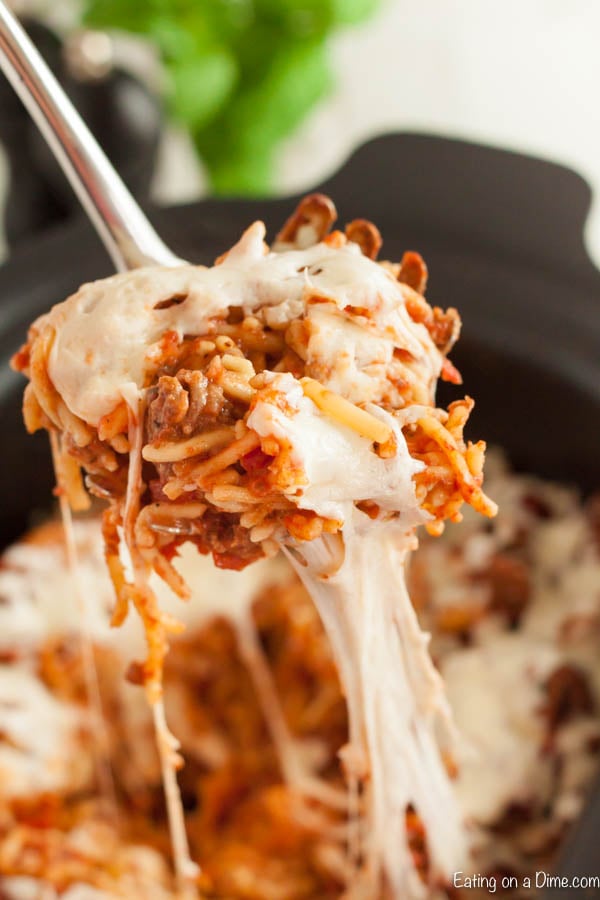 Spaghetti casserole in a slow cooker with a serving on a ladle