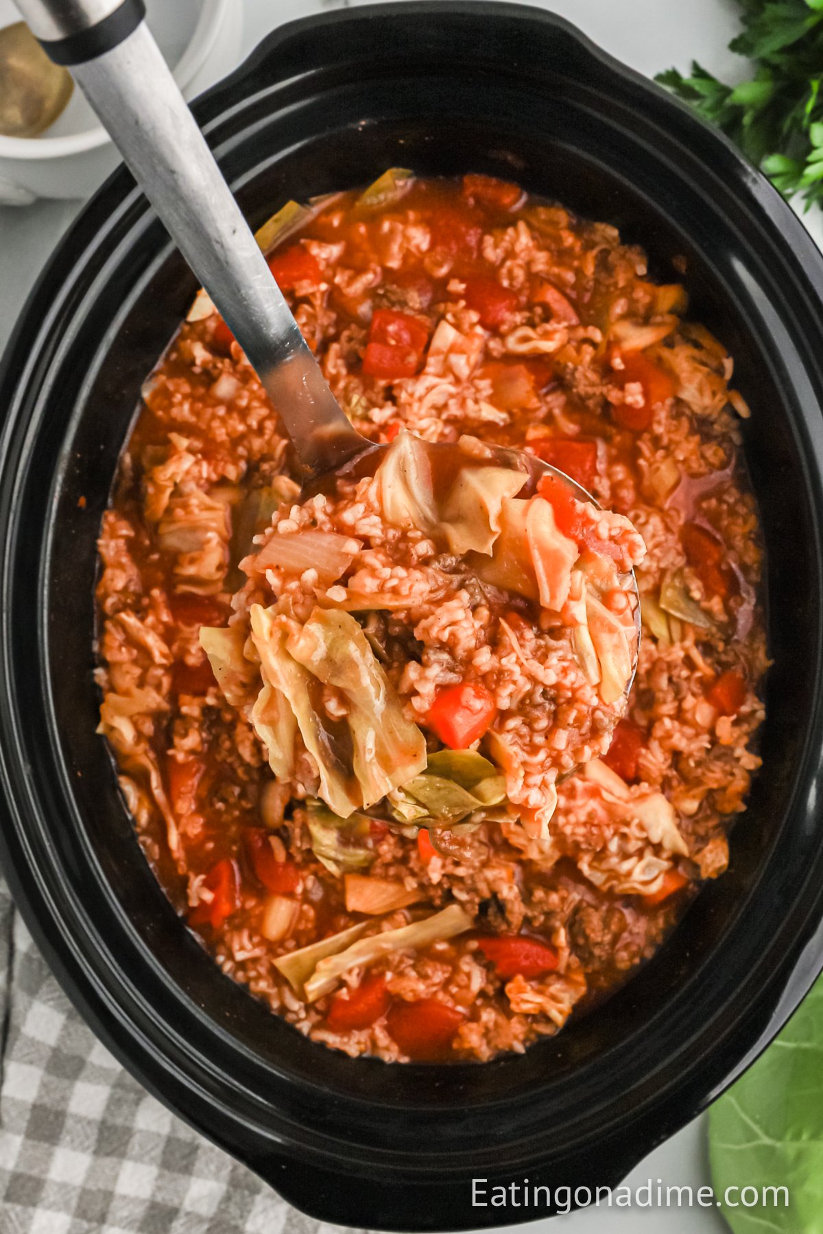 Cabbage Soup in the crock pot with a serving on the ladle