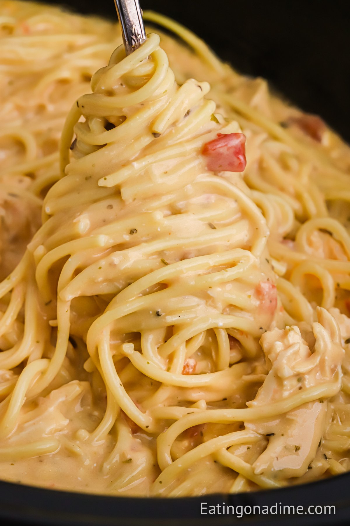 chicken spaghetti in a slow cooker with a serving on a spoon