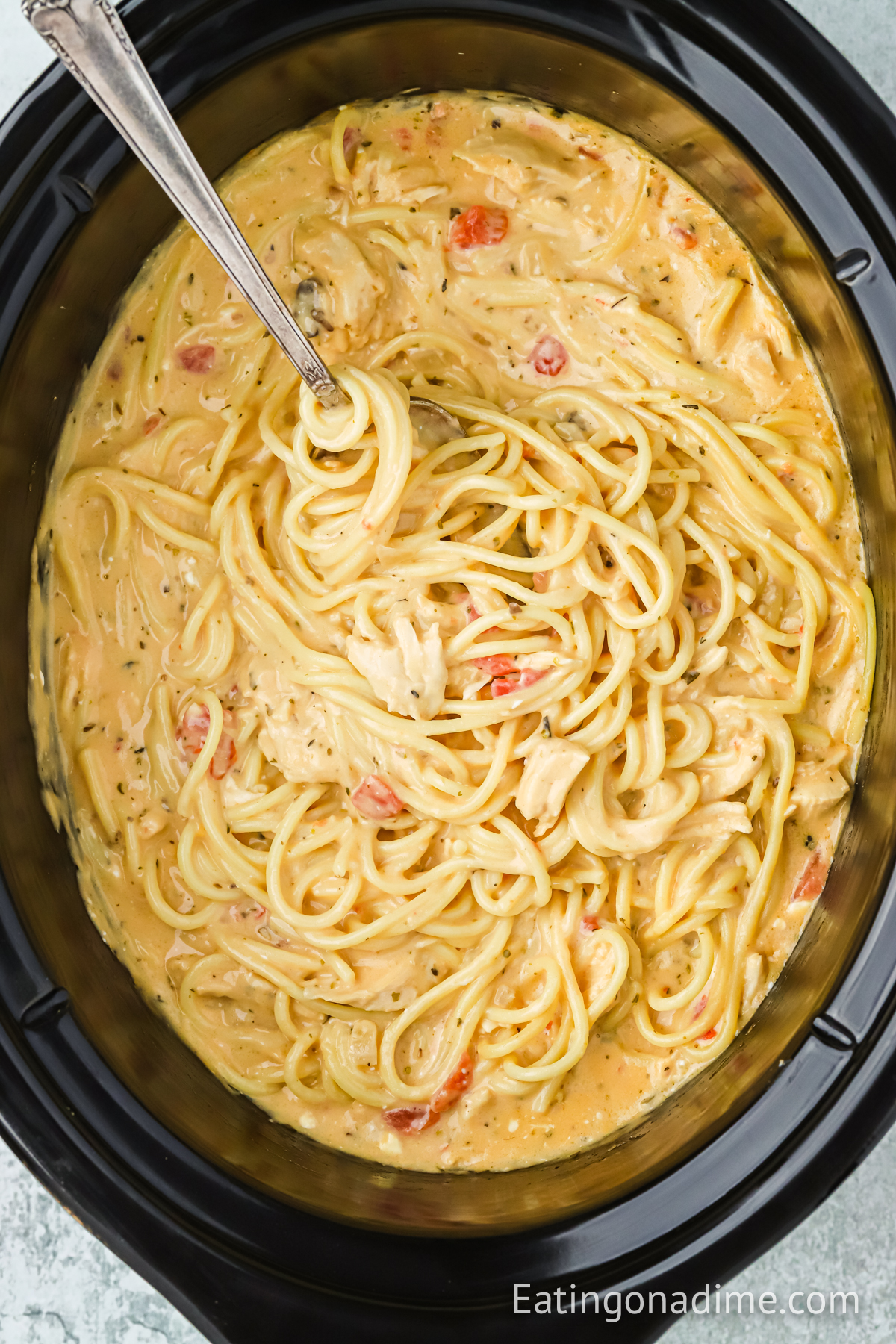 chicken spaghetti in a slow cooker with a serving on a spoon