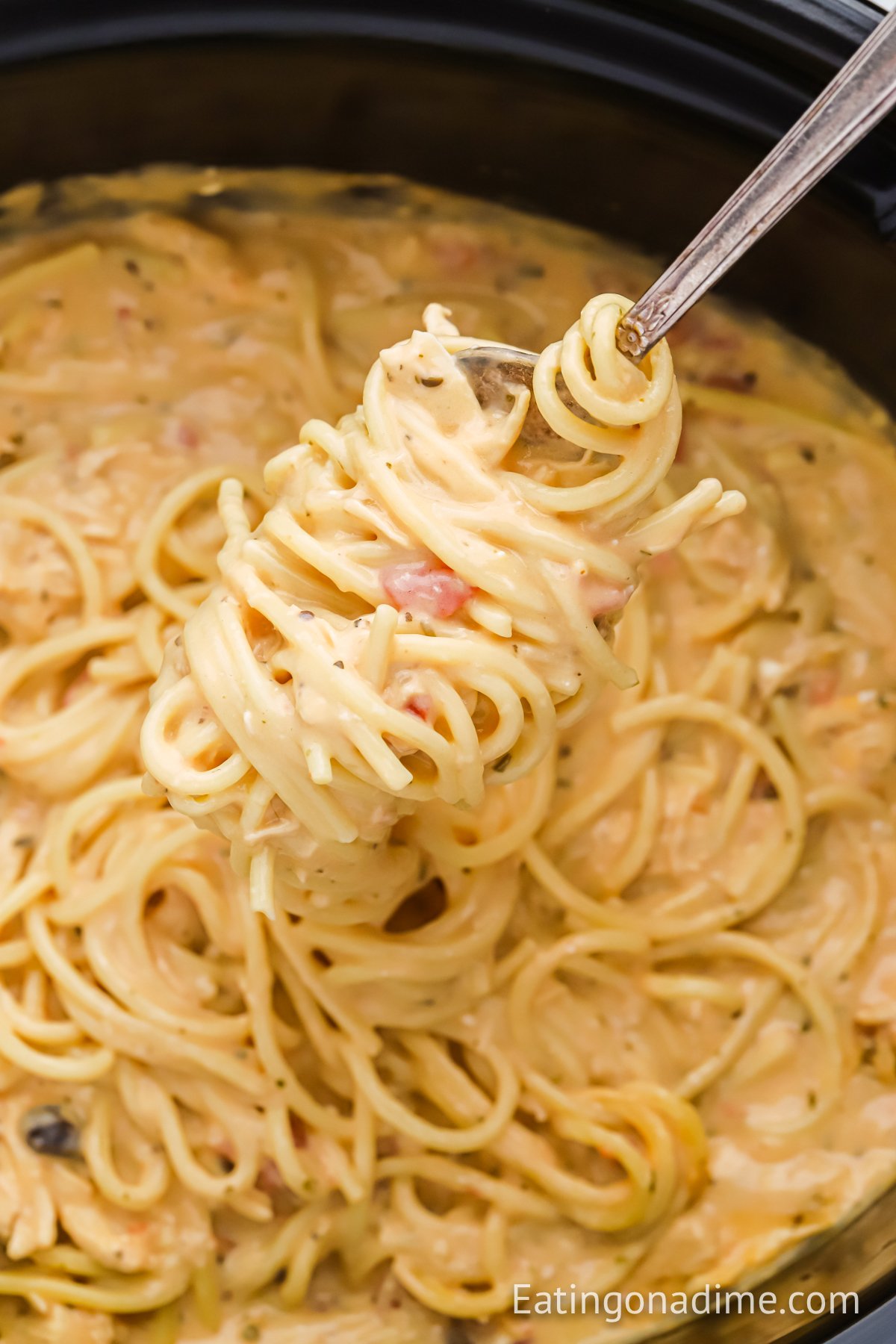 Chicken Spaghetti in slow cooker with a bite on a fork