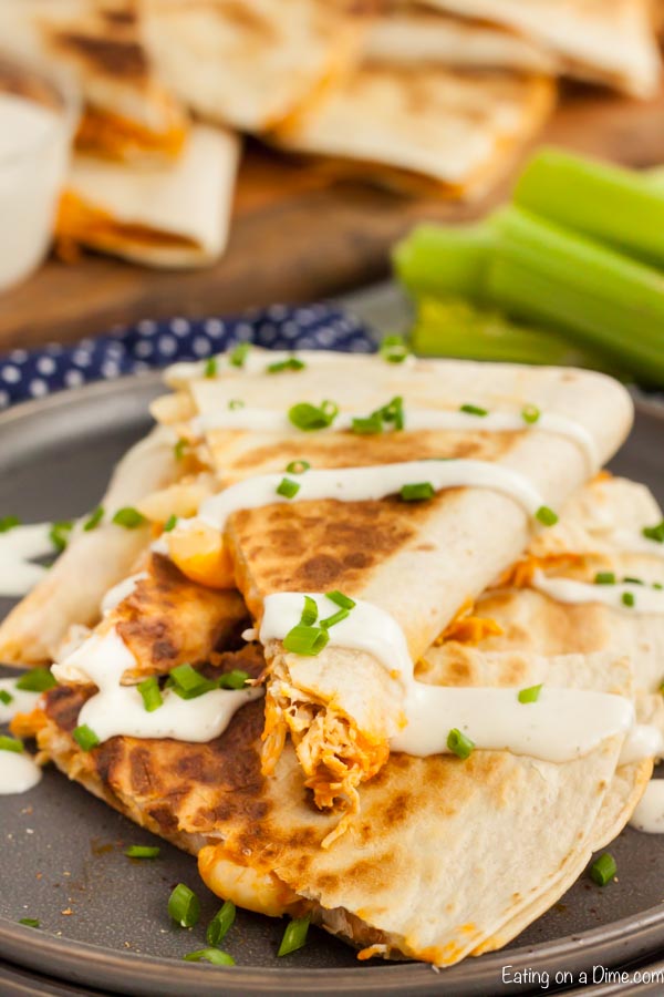 Buffalo Chicken Quesadilla slice with sour cream and green onions on a black plate