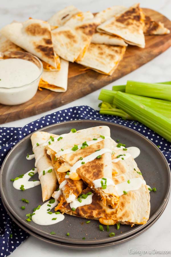 Buffalo Chicken Quesadilla slice with sour cream and green onions on a black plate