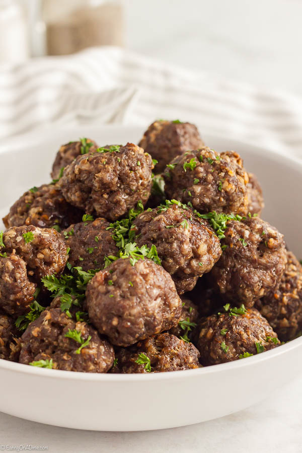 A white bowl of meatballs topped with fresh parsley 