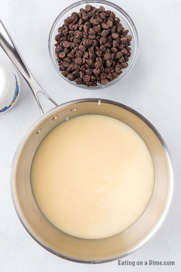 sweetened condensed milk in pan beside a bowl of chocolate chips
