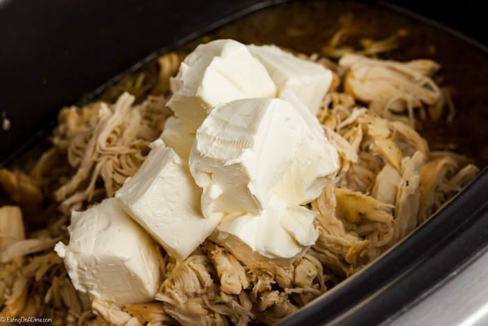 The cream cheese being stirred into a slow cooker.  