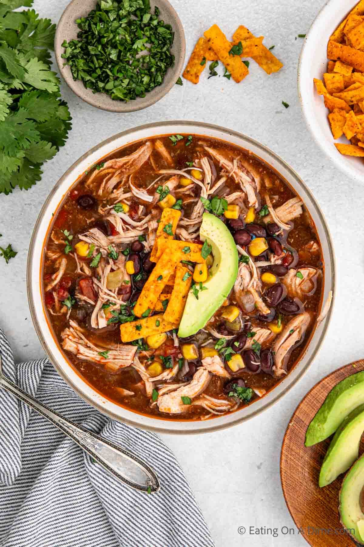Bowl of Chicken Enchilada Soup topped with slice avocados and tortilla chips