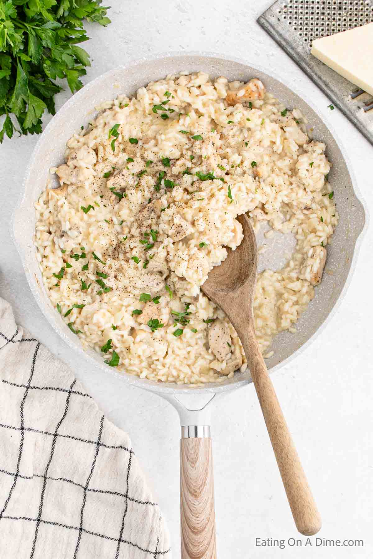 Chicken risotto in a skillet with a wooden spoon