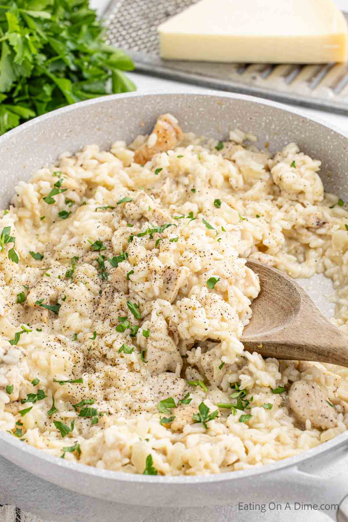 Chicken risotto in a skillet with a wooden spoon