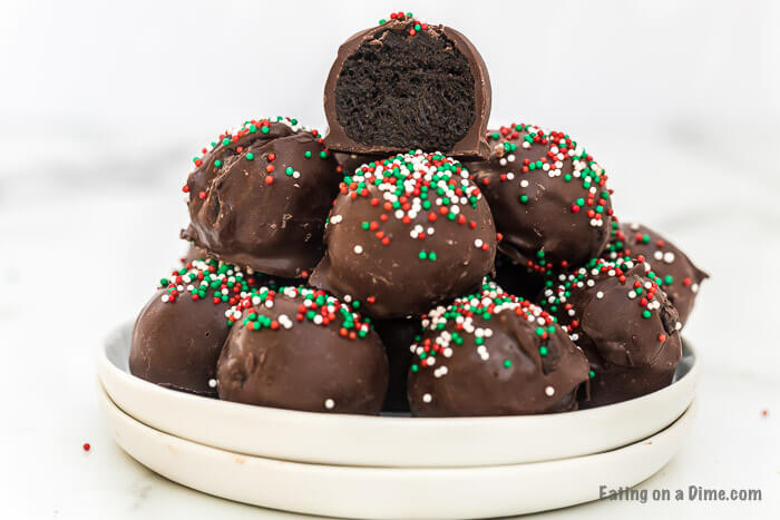 Oreo Truffles stacked on top of each other with a bite taken out of the top one so you can see the oreo mixture inside.  