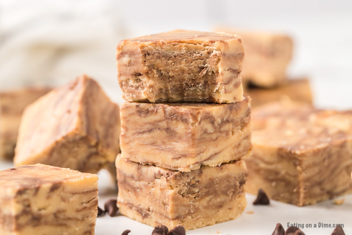 3 pieces of peanut butter chocolate chip fudge stacked on top of each other with a bite taken out of the top piece. 