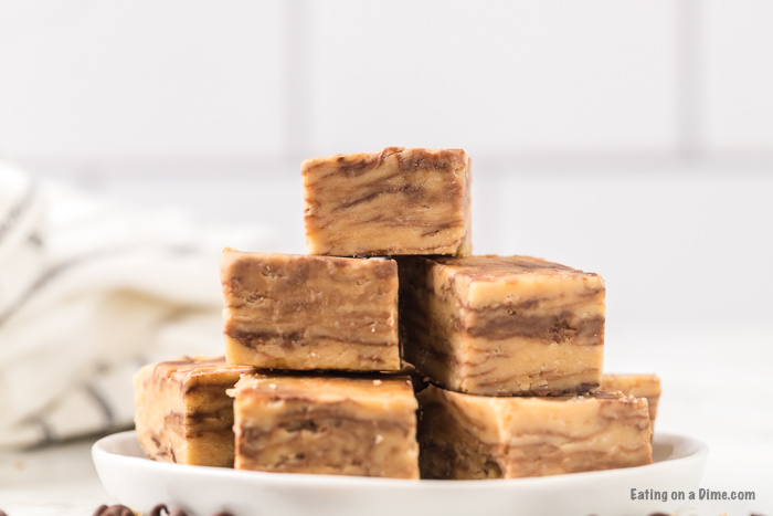 Pieces of peanut butter chocolate chip fudge stacked on top of each other on a small white plate 