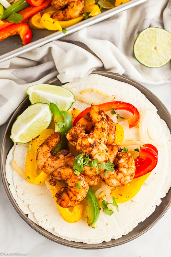 Close up image of Shrimp Fajitas on a flour tortillas with a side of fresh limes