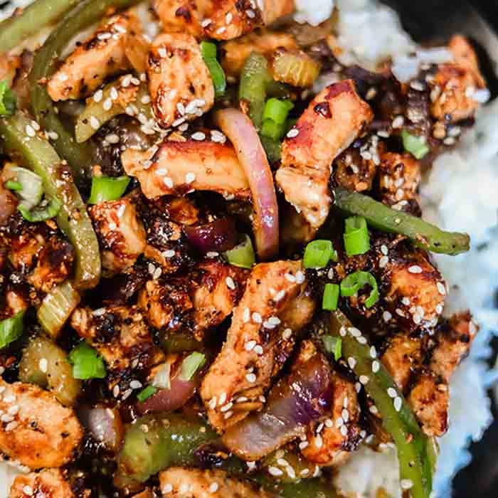 Close up image of black pepper chicken on rice. 