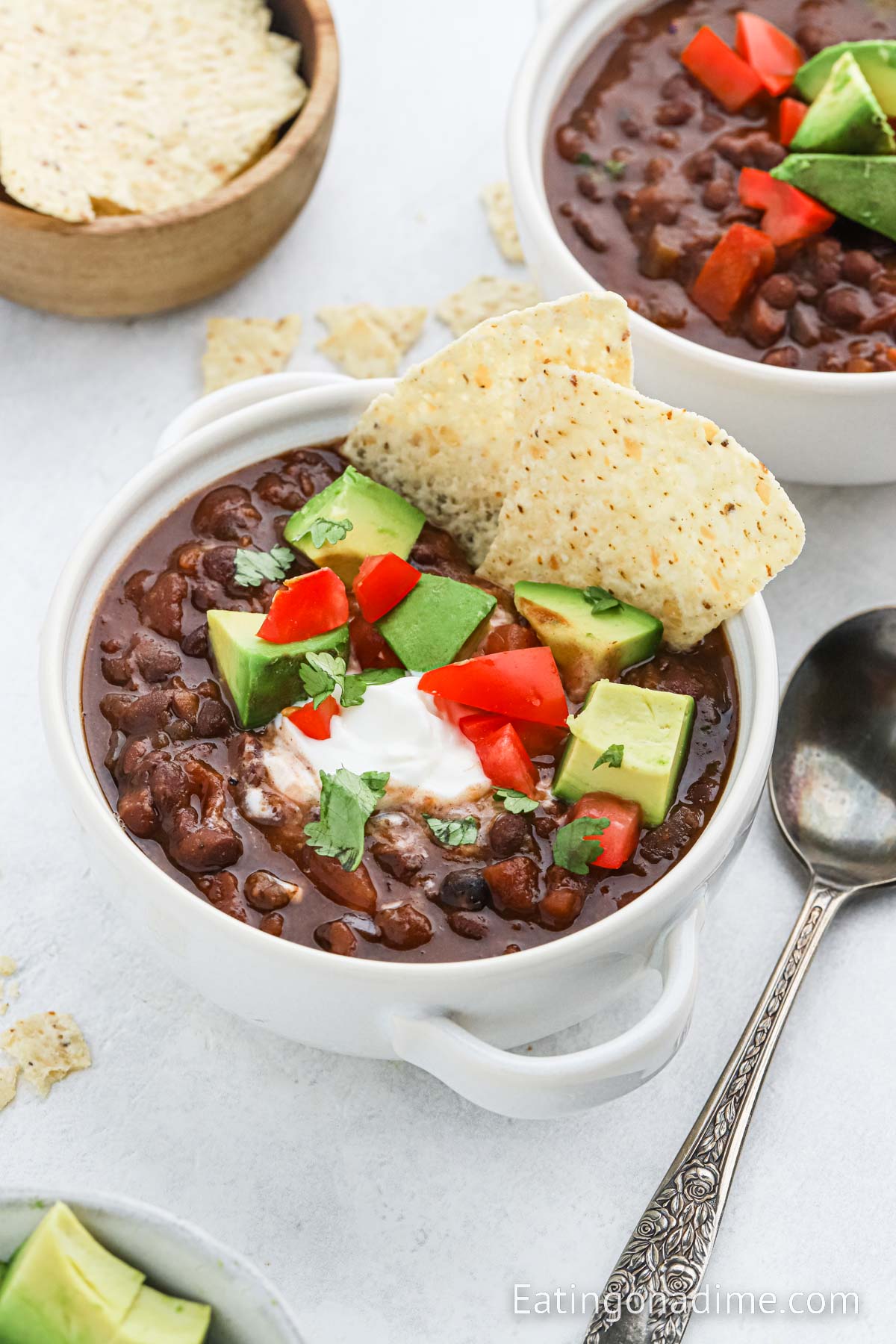 Black Beans in a bowl topped with slice avocados, sour cream and diced tomatoes and tortilla chips