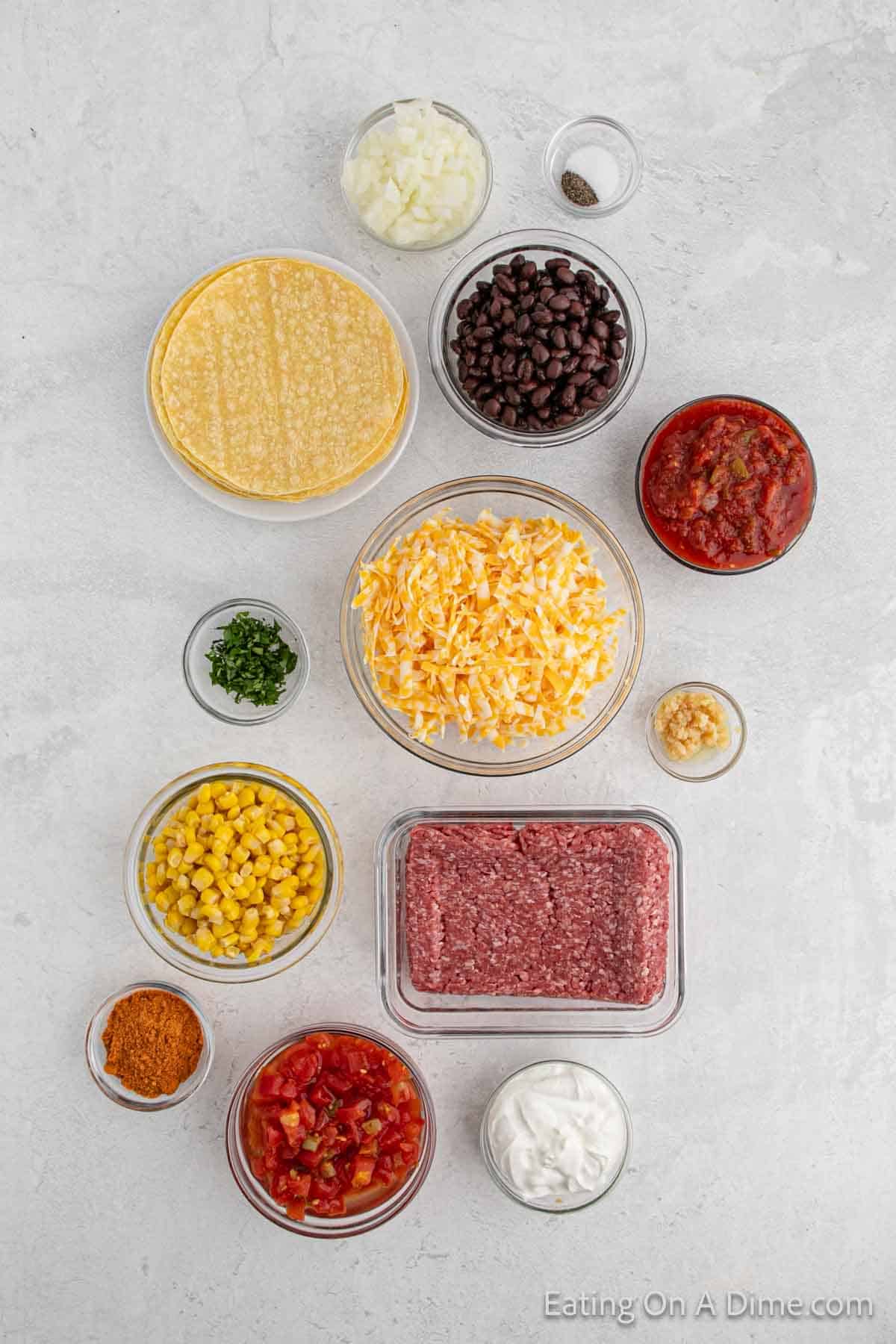 Mexican Lasagna Ingredients - Ground beef, onion, minced garlic, taco seasoning, salt, pepper, black beans, corn, diced tomatoes, salsa, cheese, corn tortillas, sour cream, fresh cilantro