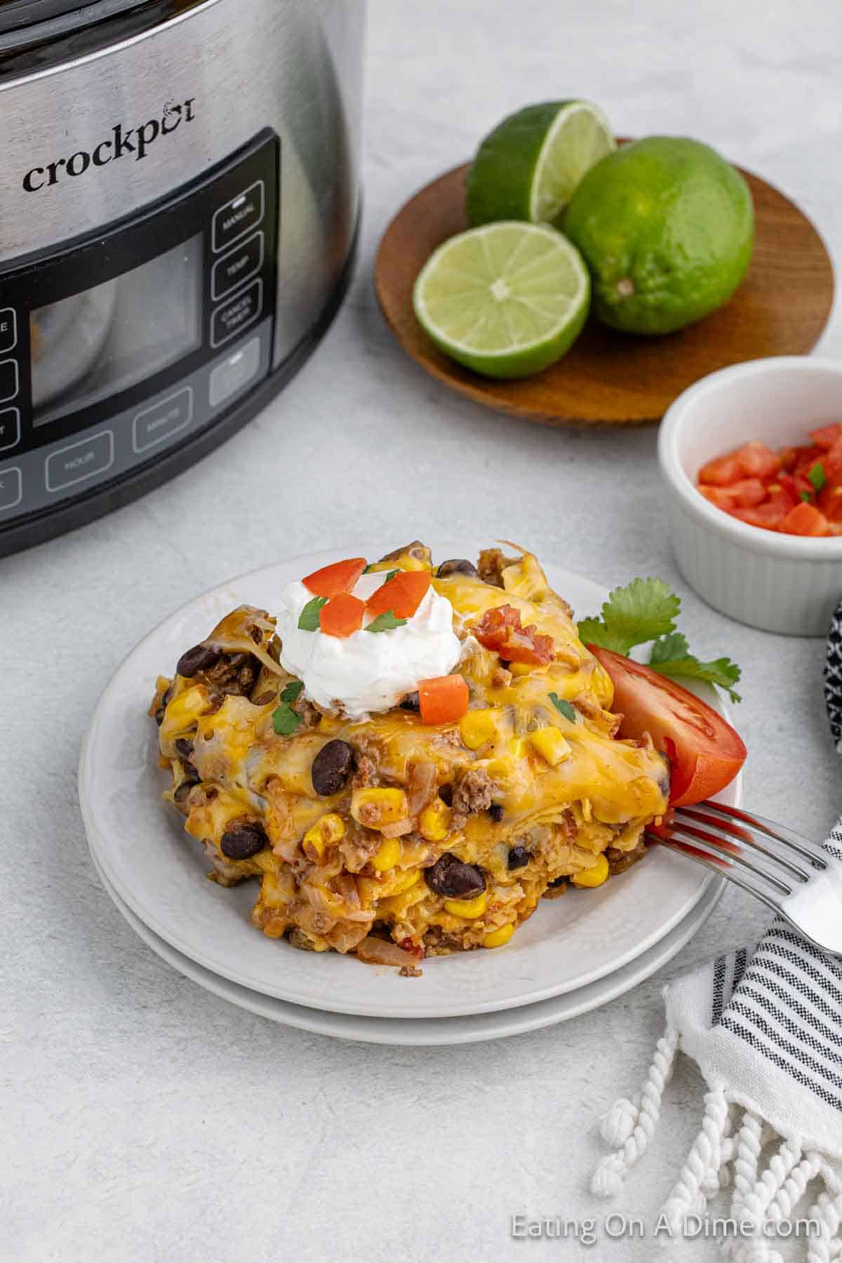 A portion of the Mexican Lasagna on a plate topped with sour cream and diced tomatoes