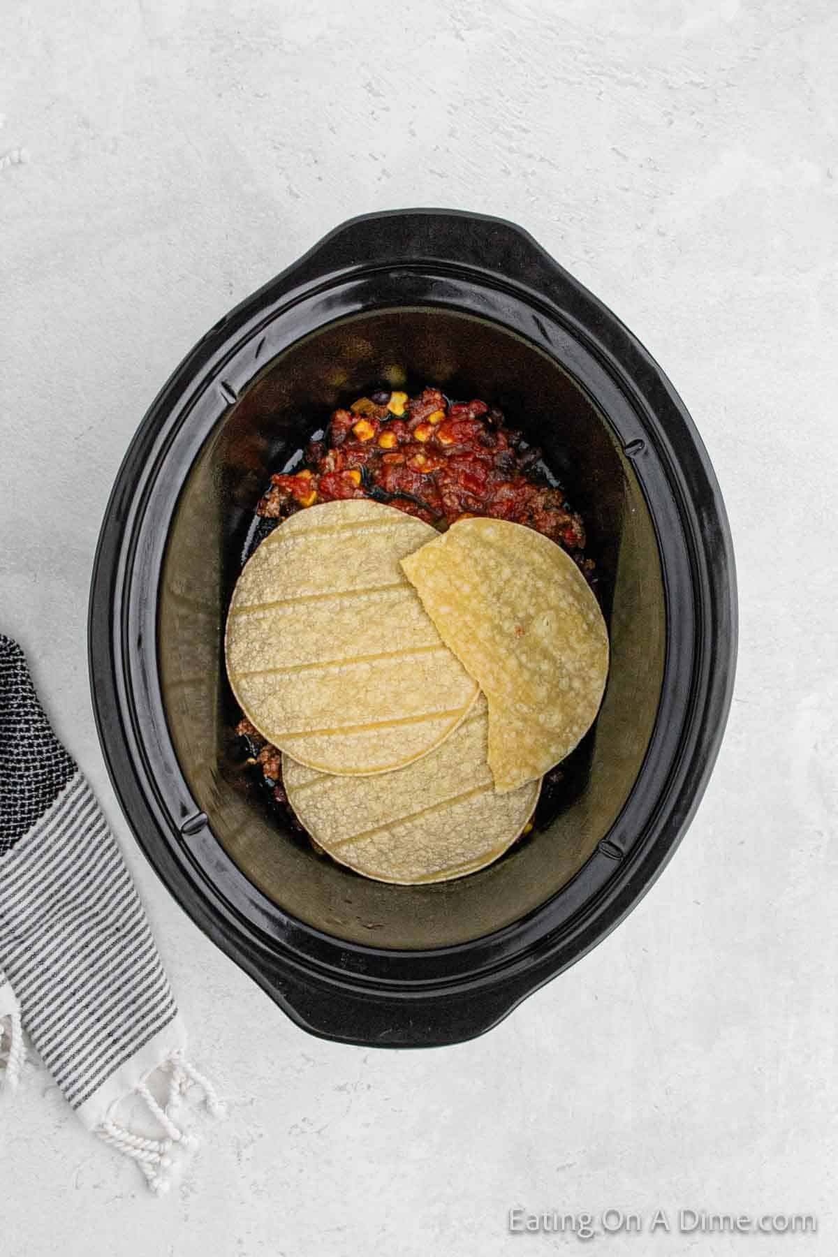 Topping the beef mixture with corn tortillas