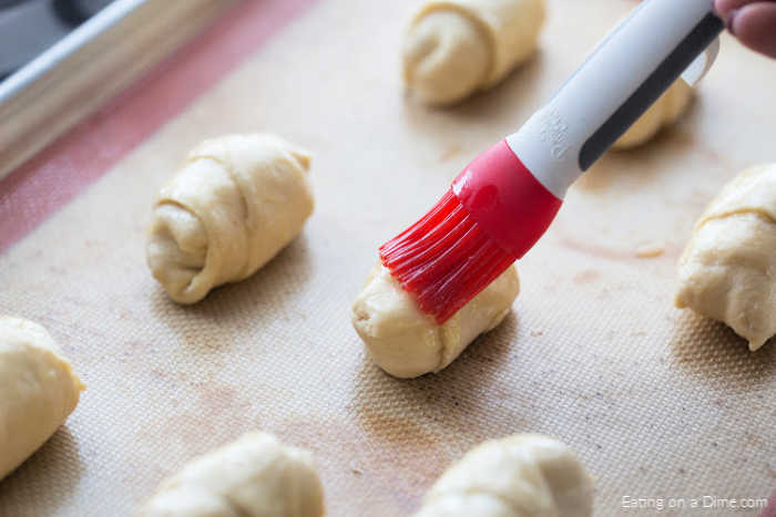 Brushing melted butter over the tops of the crescent rolls