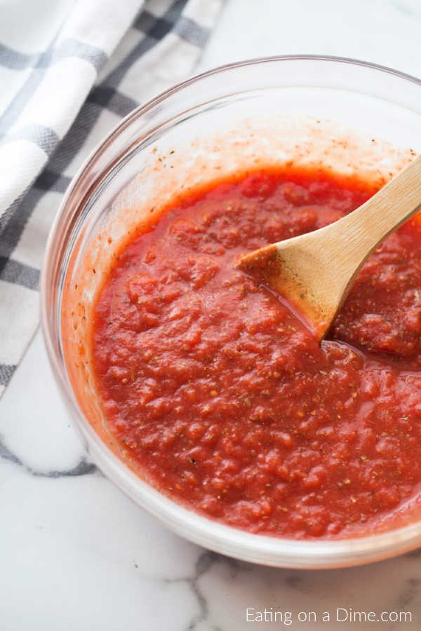 A bowl of marinara sauce with a wooden spoon