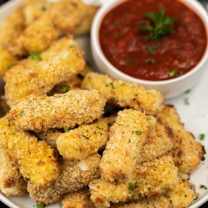 Homemade cheese stick on a plate with a bowl of marinara sauce