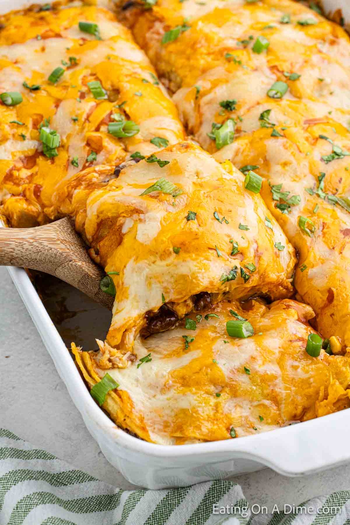 Close up image of chicken enchilada casserole with a wooden spoon