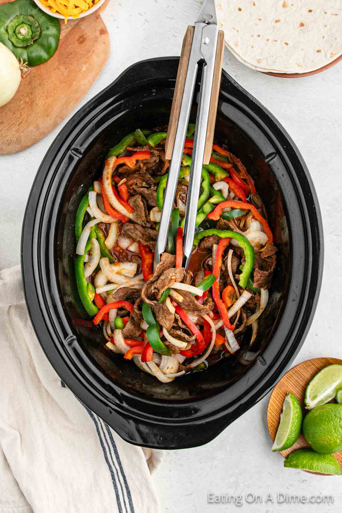 Steak fajitas in the slow cooker with tongs