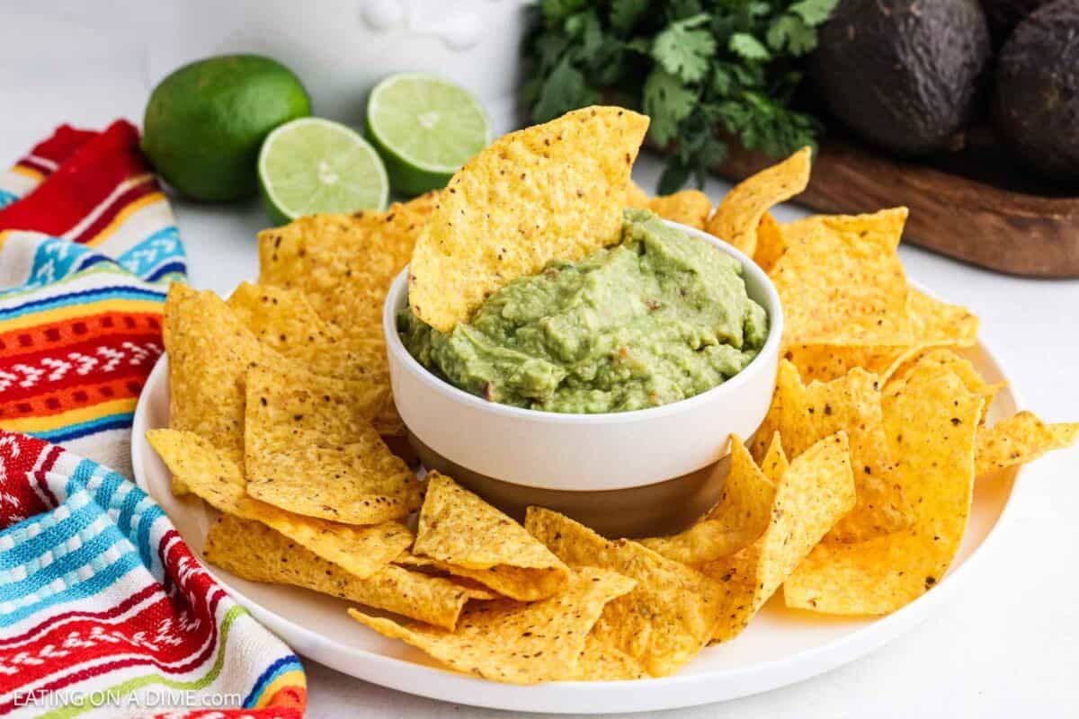 Homemade Guacamole in a white dish surrounded by tortilla chips.