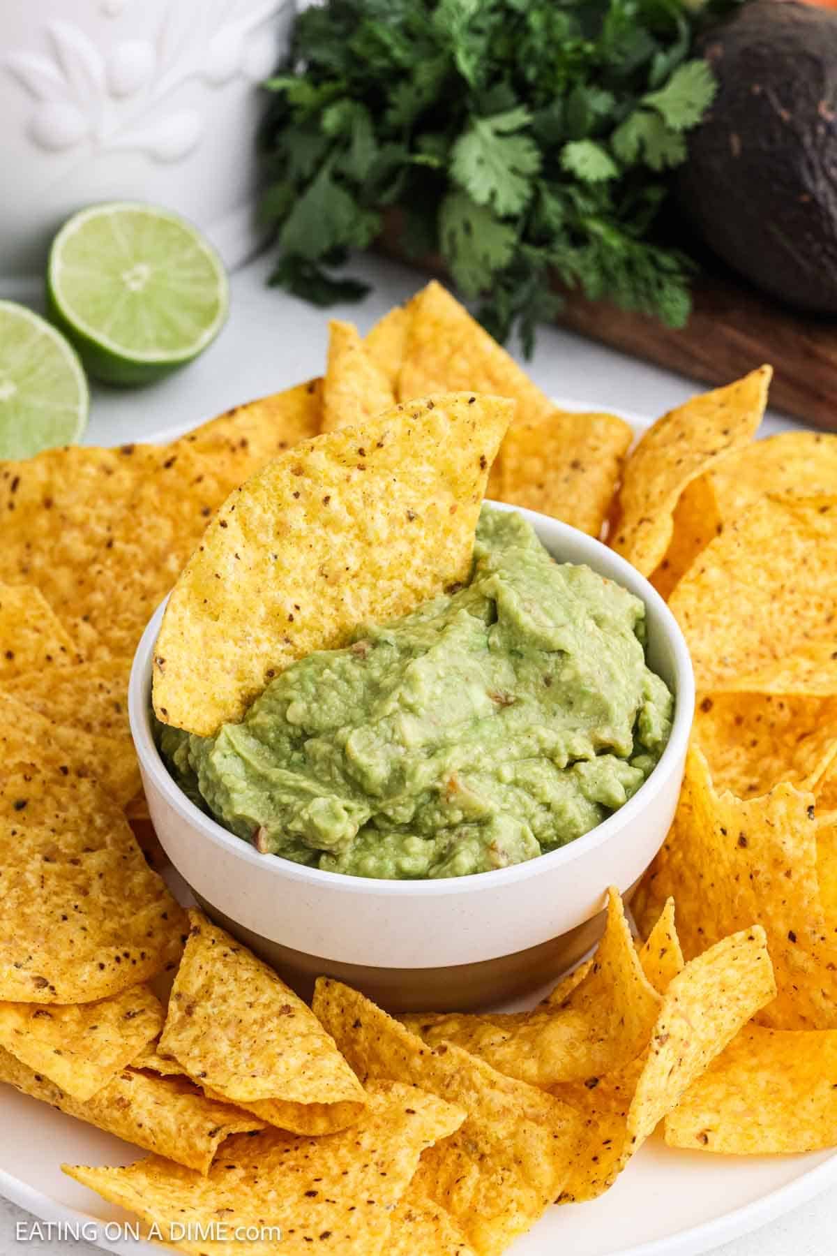 Ready to serve dip in a bowl with tortilla chips surrounding the guacamole.