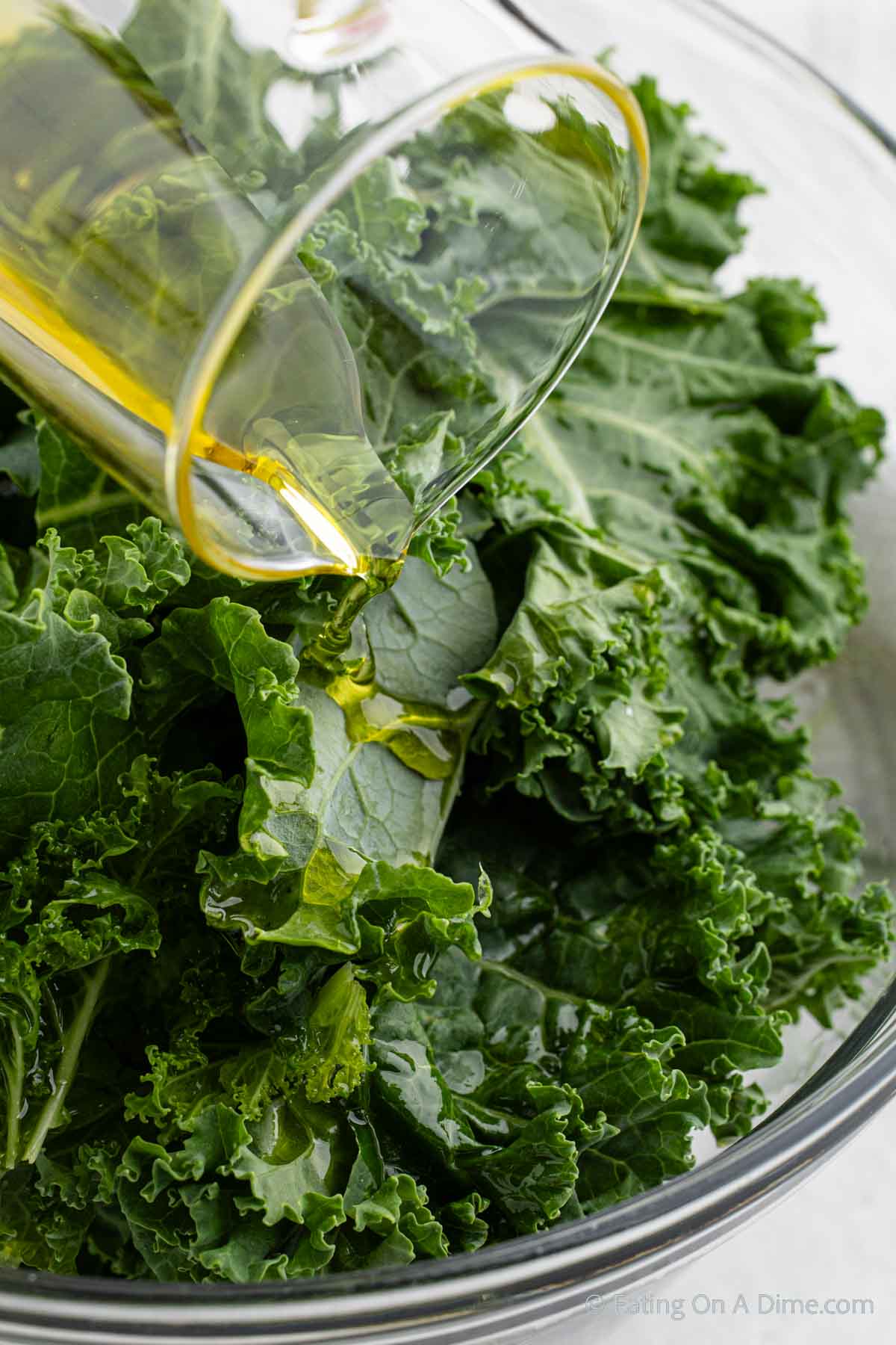 Pouring oil on the kale in a bowl