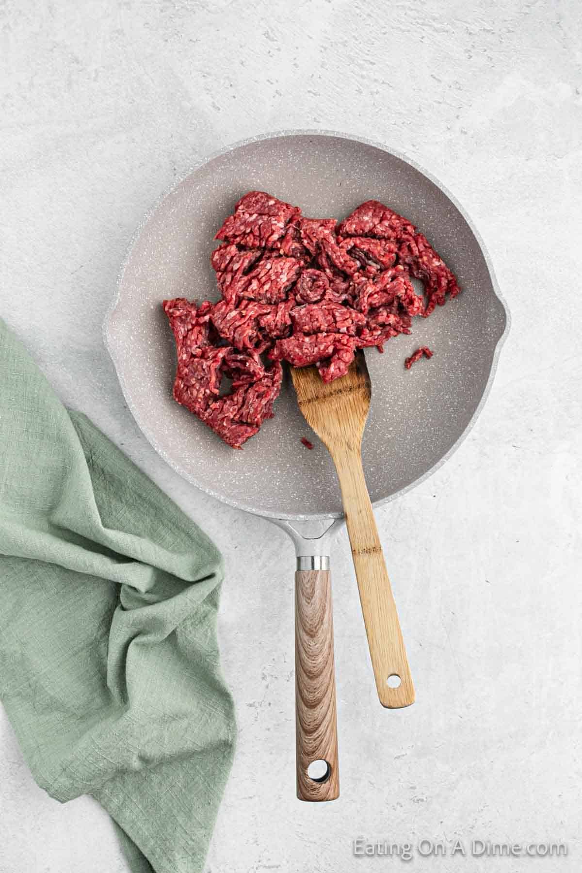 Cooking ground beef in a skillet with wooden spoon