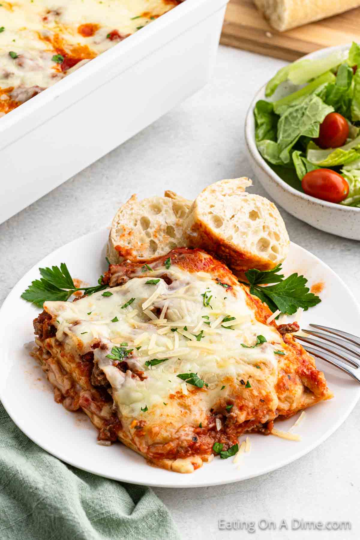 A serving of Ravioli Lasagna on a plate with two slices of bread