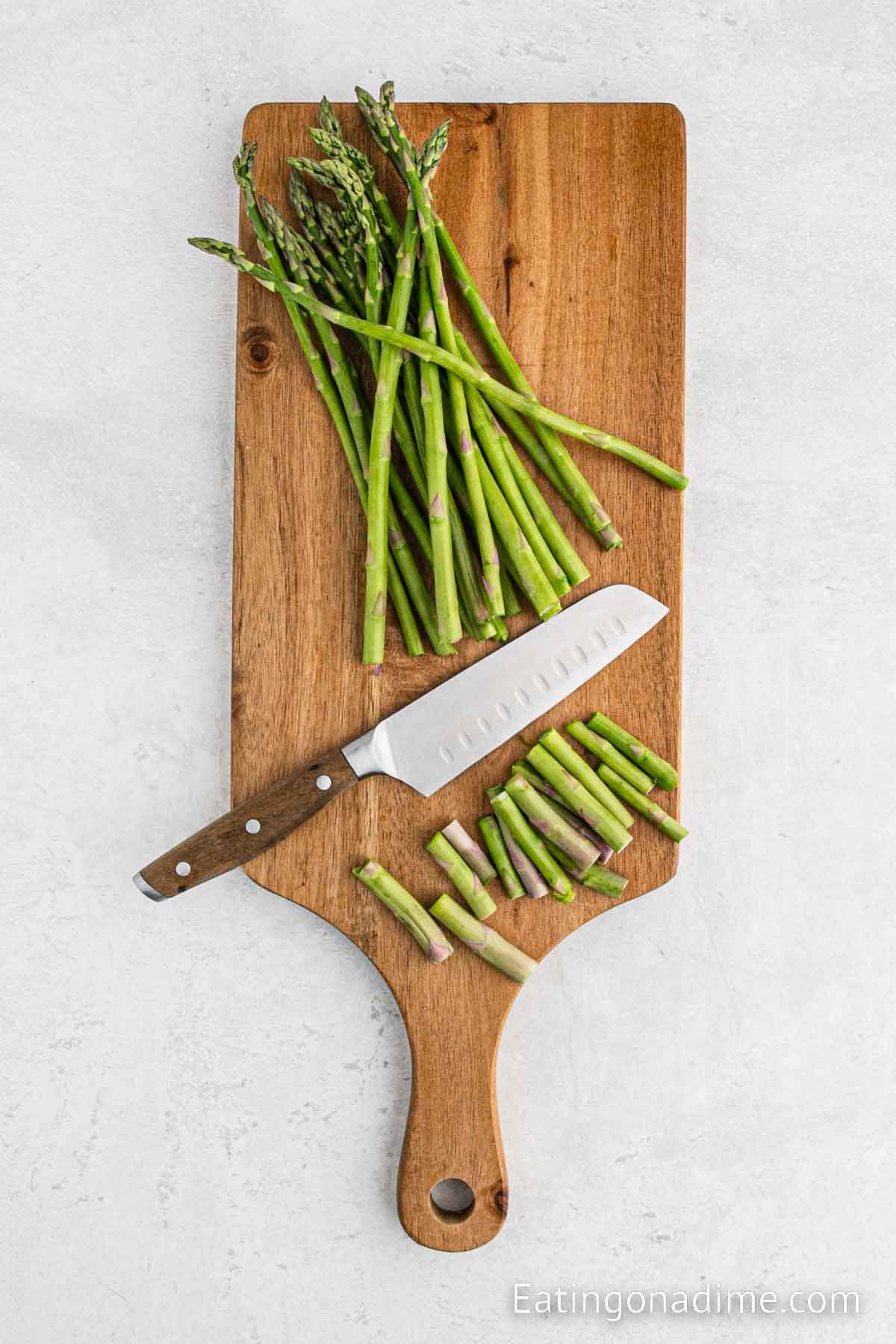 Trimming the asparagus woody ends on a cutting board with a sharp knife