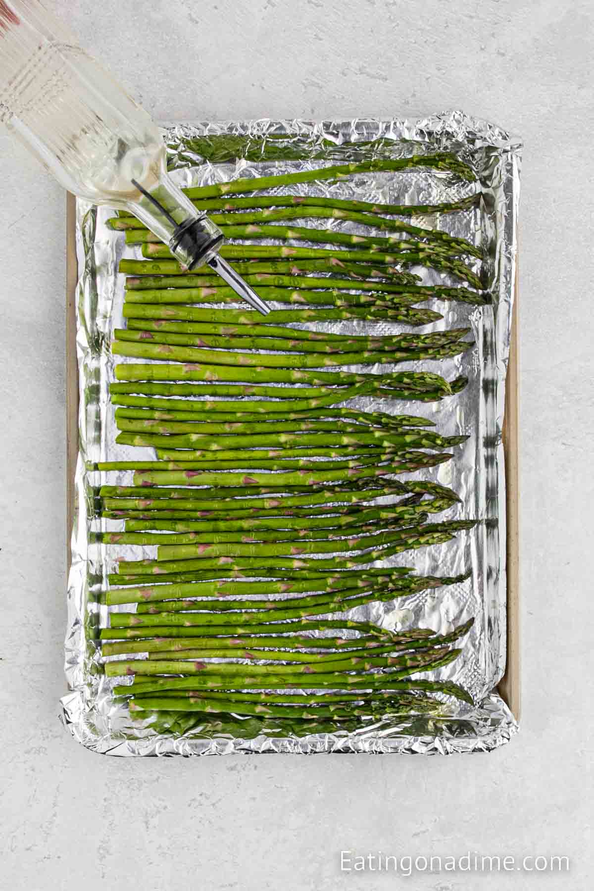 Drizzling oil over the asparagus on a baking sheet