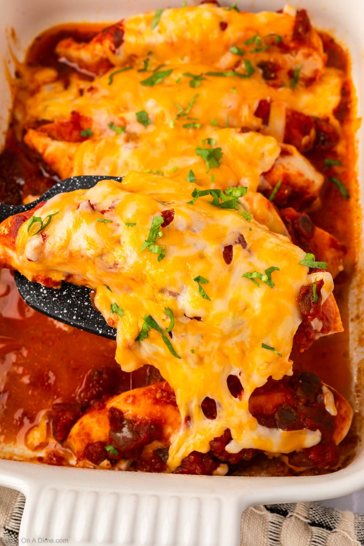 Baked salsa chicken in a casserole dish with a serving on a spatula