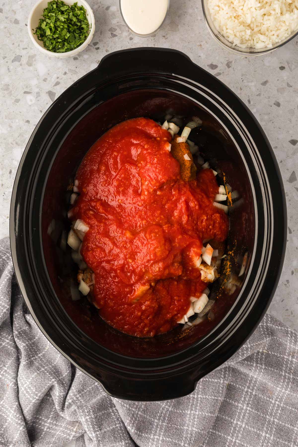 Topping the chicken with sauce and onions in the slow cooker