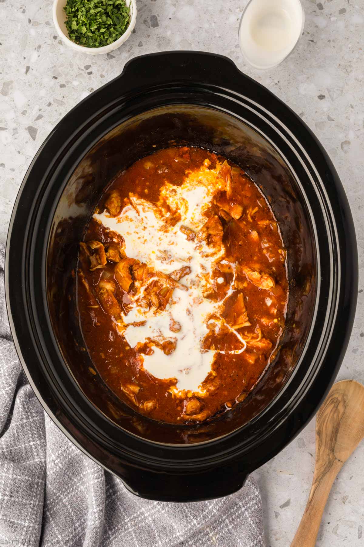 Pouring heavy cream in the tomato sauce with the chicken