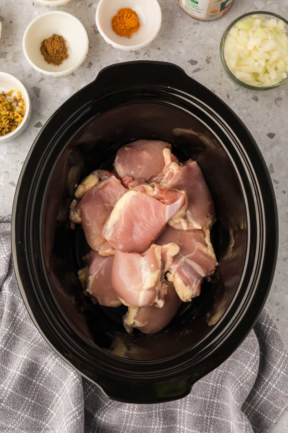 Placing chicken thighs in the slow cooker 