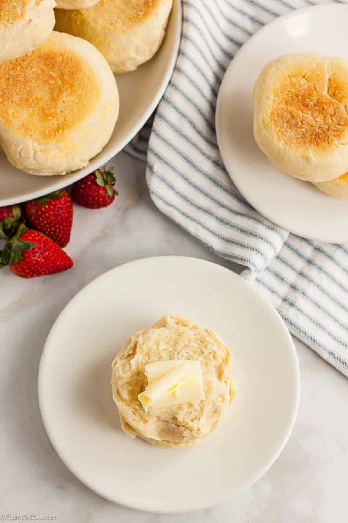 English muffins sliced and topped with butter on a plate 