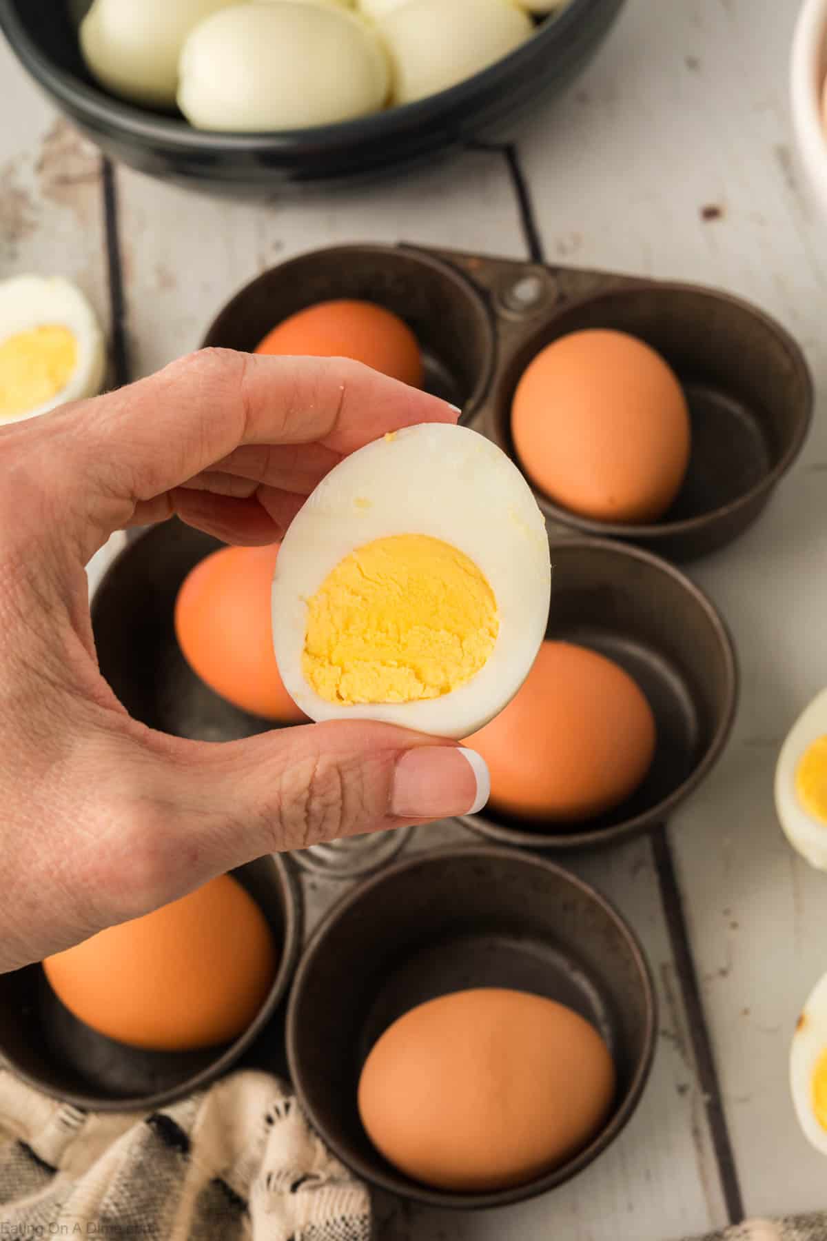 Close up image of hard boiled eggs and eggs in the background in a muffin tin