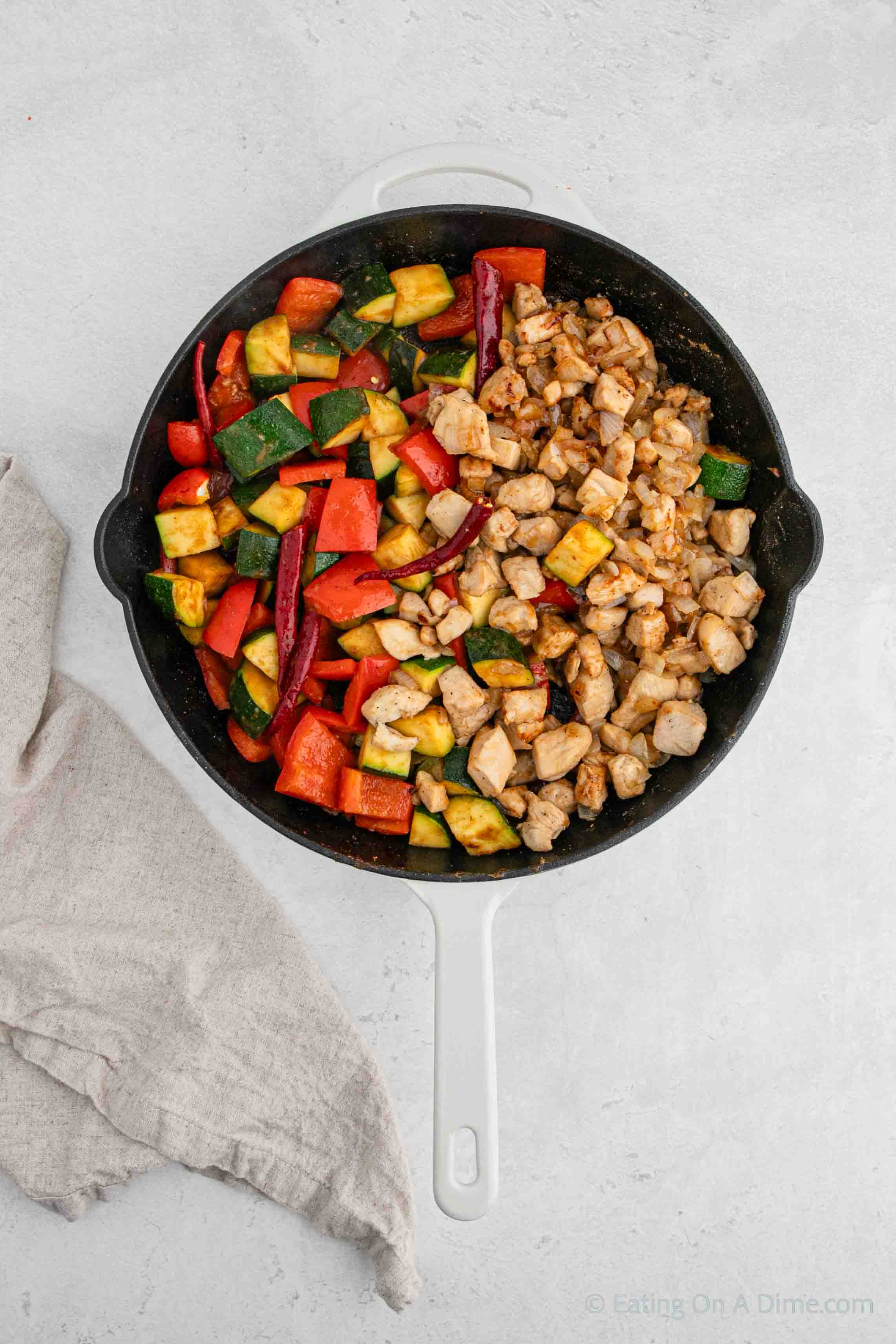 Cooked diced chicken and roasted vegetables in a skillet