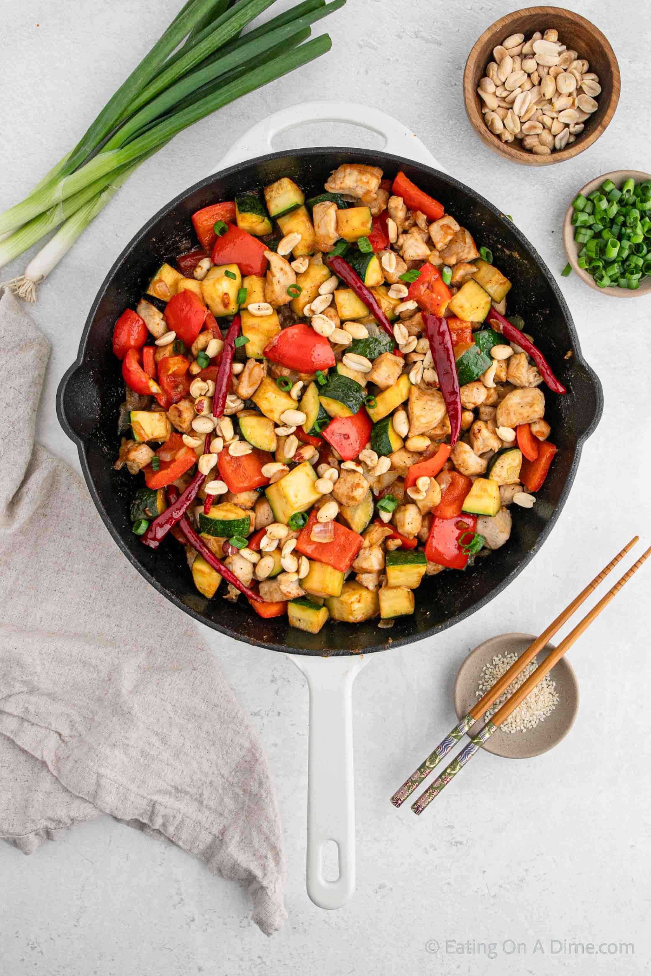 Kung Pao Chicken in a cast iron skillet topped with peanuts