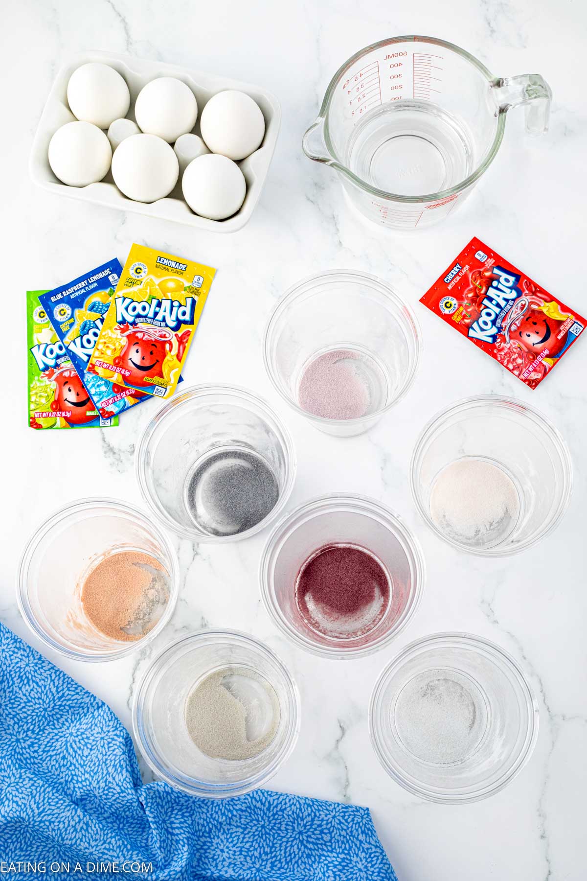 Placing the koolaid packets in cups with a carton of eggs