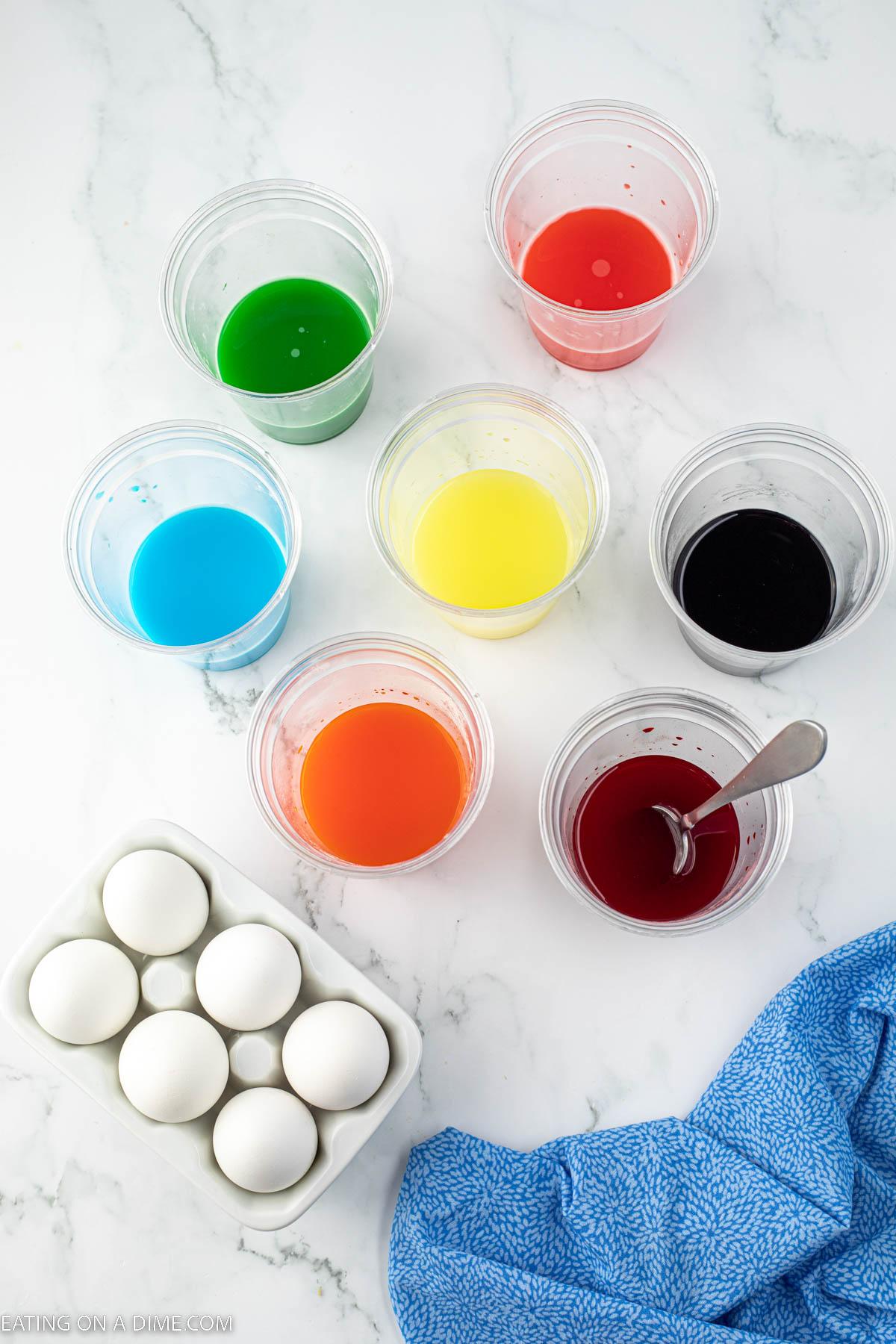 Cups of colored water with a carton of eggs