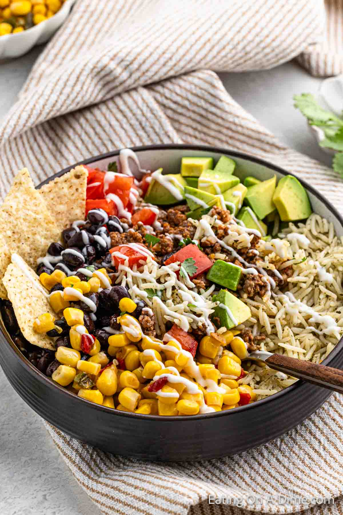 Taco Bowl topped with slice avocados sour cream corn salsa and tortilla chips