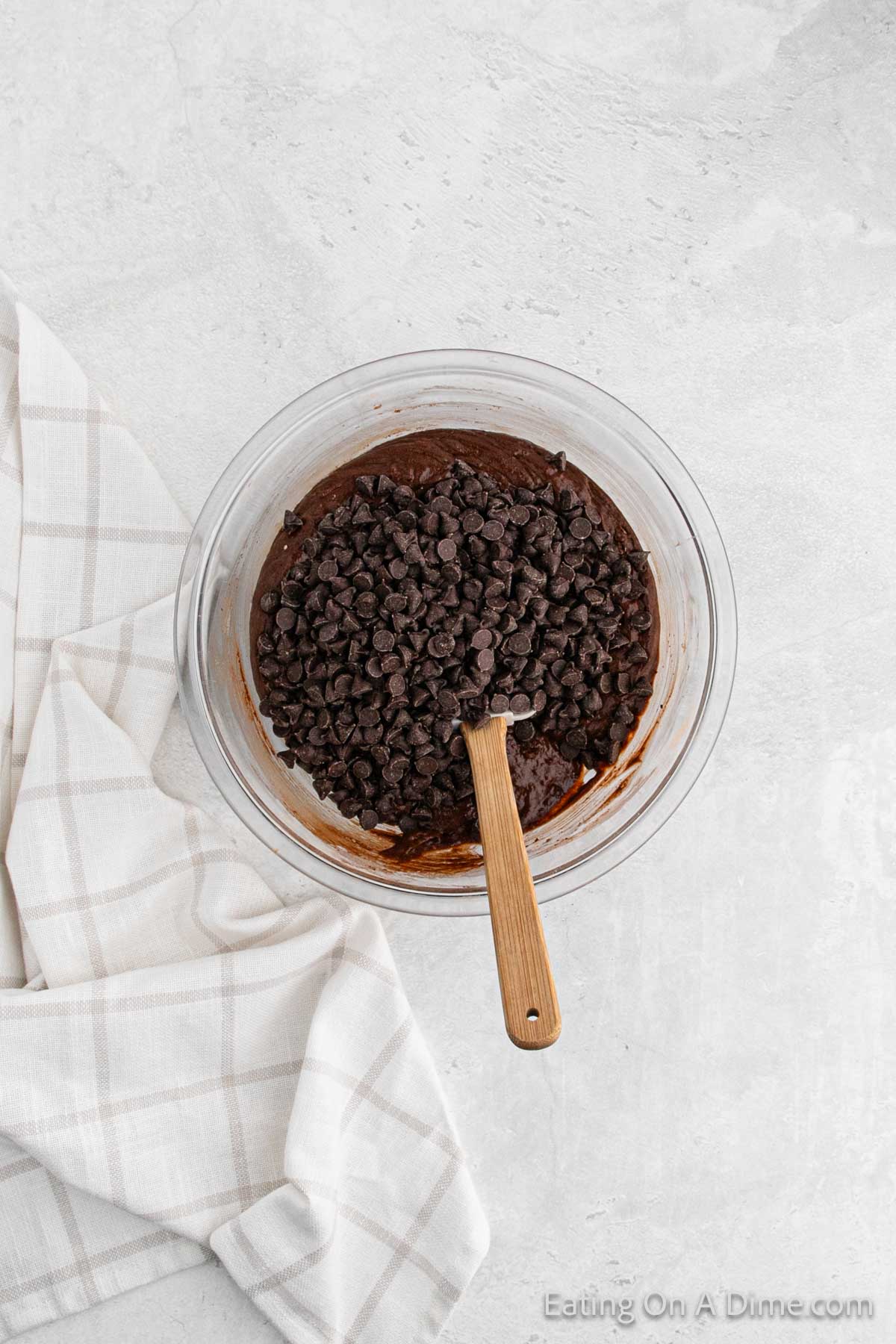Chocolate chip being mixed with the chocolate batter in a bowl with a spatula