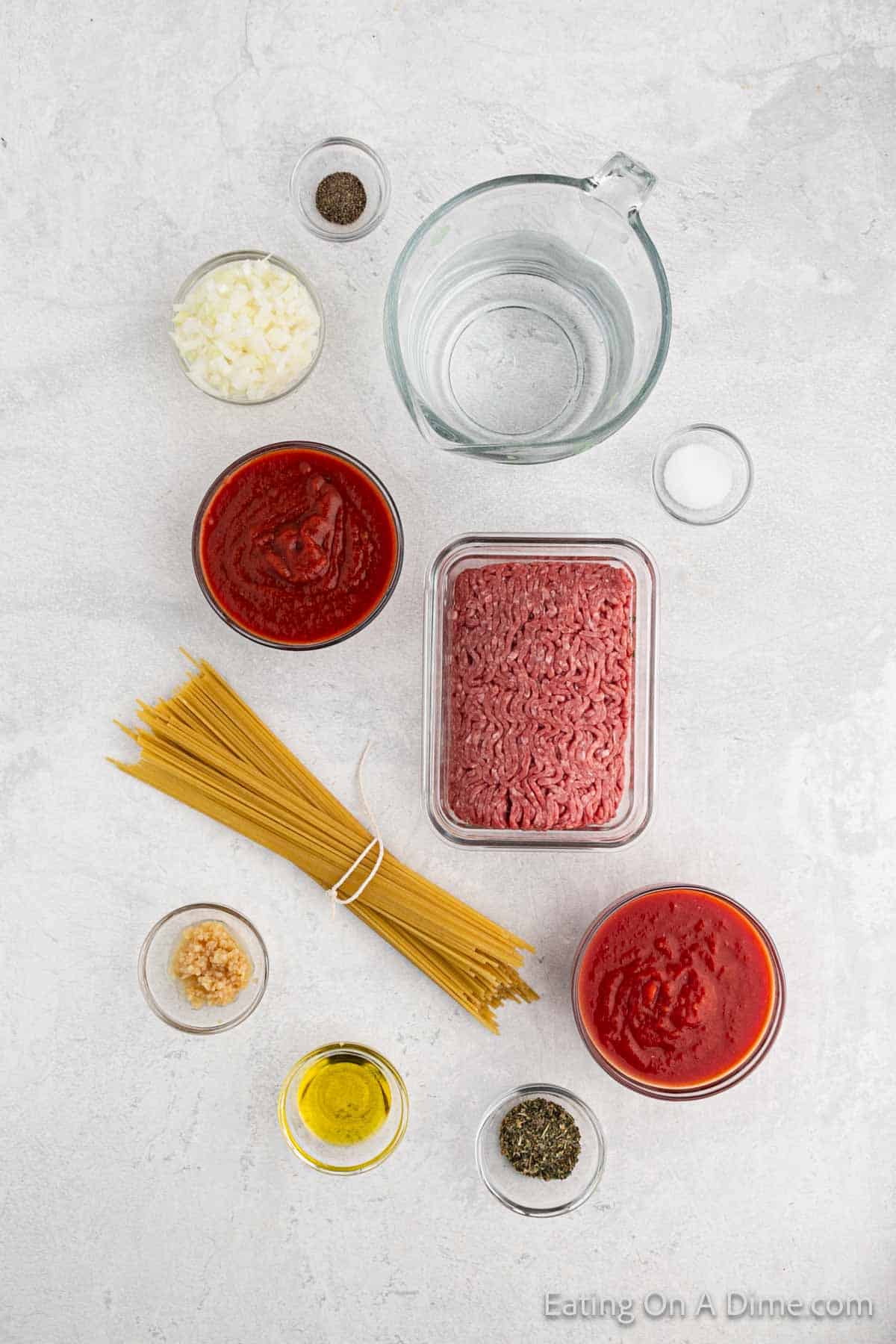 Instant pot spaghetti ingredients - olive oil, onion, minced garlic, ground beef, salt, pepper, italian seasoning, crushed tomatoes, tomato sauce, water, spaghetti noodles