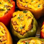 Colorful bell peppers stuffed with a savory ground meat mixture, topped with melted cheddar cheese and fresh herbs. This Instant Pot stuffed peppers recipe features red, yellow, and green peppers for a delicious and vibrant meal.